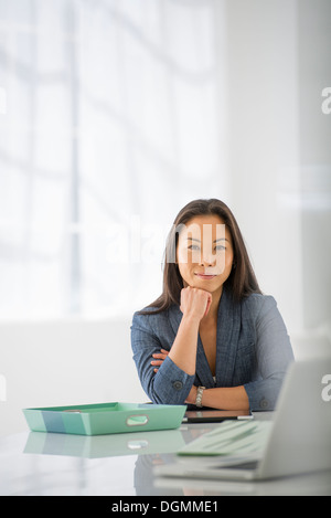 L'entreprise. Une femme assise, de détente avec son menton sur sa main. Banque D'Images