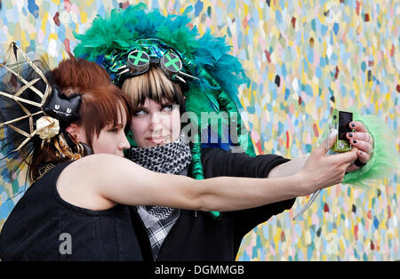 Deux jeunes femmes avec une coiffure bizarre photographier eux-mêmes avec leur téléphone mobile, costumes imaginatifs, cosplayeurs Banque D'Images