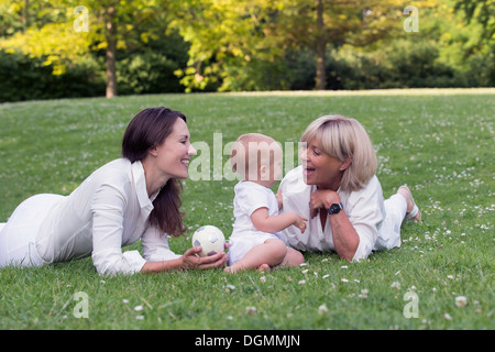 Pays Bas, Hollande-du-Sud, Oud-Beijerland, grand-mère avec la mère et sa petite-fille (12-17 mois) jouant sur l'herbe Banque D'Images
