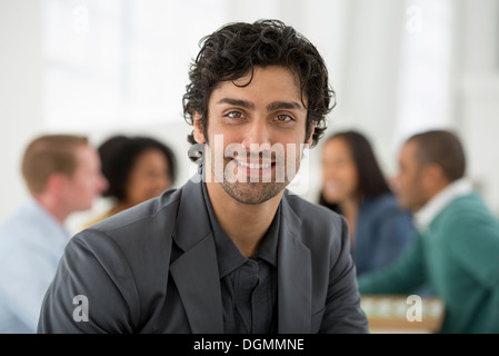 Réunion d'affaires. Un groupe assis autour d'une table. Un homme souriant en toute confiance. Banque D'Images