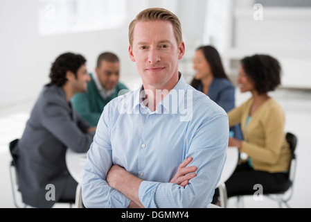 Réunion d'affaires. Un groupe assis autour d'une table. Un homme souriant en toute confiance. Banque D'Images