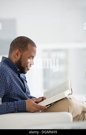 Une lumière blanche intérieur. Un homme en train de lire un livre. Banque D'Images