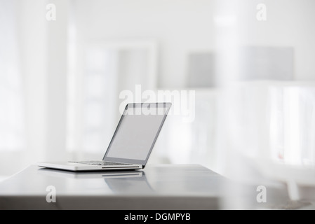 L'intérieur du bureau. Un brillant lisse table gris, et un ordinateur portable. Banque D'Images