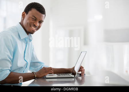 L'intérieur du bureau. Un homme assis à une table, à l'aide d'un ordinateur portable.