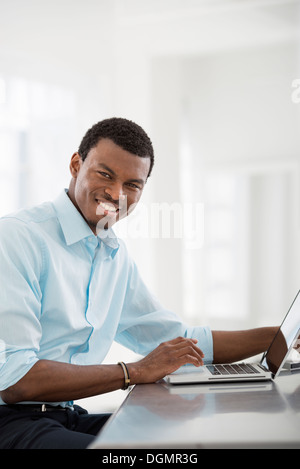 L'intérieur du bureau. Un homme assis à une table, à l'aide d'un ordinateur portable.