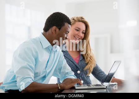 L'intérieur du bureau. Un couple assis côte à côte à un ordinateur. Banque D'Images
