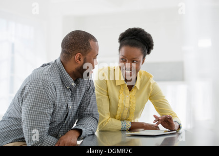 L'intérieur du bureau. Deux personnes, un couple à une table à l'aide d'une tablette numérique. Banque D'Images