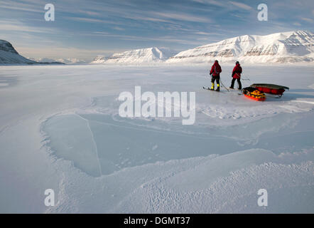 Les skieurs de fond avec pulkas pour traverser un fjord gelé, Tempelfjorden, Spitsbergen, Svalbard, Norvège, Europe Banque D'Images