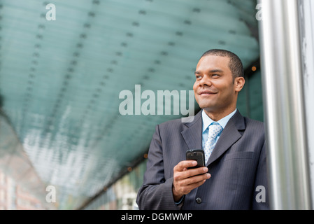 Ville. Un homme dans un costume d'affaires vérifier ses messages sur son téléphone intelligent. Banque D'Images