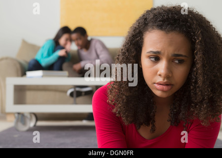 Girl (12-13) pleurer alors que deux adolescents (14-15, 16-17) murmurer derrière elle Banque D'Images
