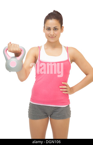 Happy sporty brunette holding kettlebell gris et rose Banque D'Images