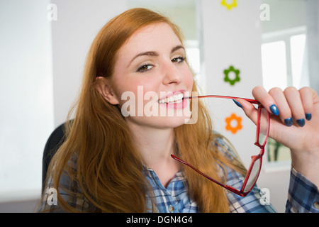 Heureux redhead mordant sa lunettes de lecture Banque D'Images