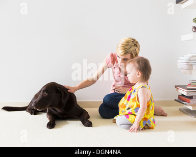 Mère avec bébé fille (4-5) Playing with dog Banque D'Images