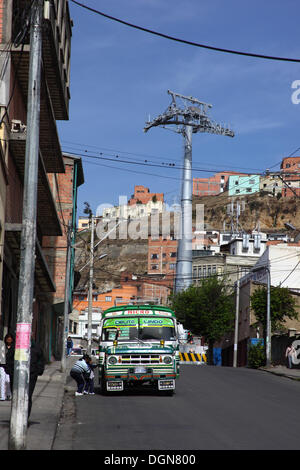 LA PAZ, BOLIVIE, 23 Oct, 2013. Les passagers à bord d'un bus public micro en face de l'un des pylônes de la nouvelle télécabine téléphérique / actuellement en construction pour relier les villes de La Paz et El Alto. Le système est construit par la société autrichienne Doppelmayr au coût de 234,6 millions de dollars financé par le gouvernement bolivien. Credit : James Brunker / Alamy Live News Banque D'Images