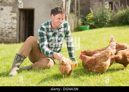 Jeune homme à nourrir ses poulets Banque D'Images