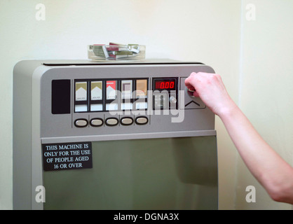 Une femme de mettre l'argent dans une machine à cigarettes, Close up Banque D'Images