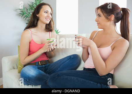 Jolies jeunes femmes tasses sitting on a couch Banque D'Images