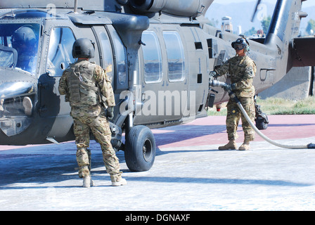 Le s.. Matthew Clark, un fantassin par le commerce, servant actuellement comme un Black Hawk UH-60M chef d'équipage de l'hélicoptère et de l'Administration centrale l'Administration centrale pour l'Entreprise, 10e Brigade d'aviation de combat, regarde un spécialiste d'approvisionnement en pétrole de l'Alaska La Gu Banque D'Images