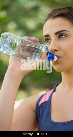 Monter cute woman wearing sportswear drinking from bottle Banque D'Images