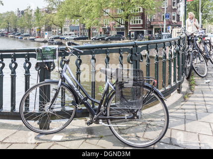 Vélo hollandais enchaînés à des garde-corps sur un pont à Amsterdam, Hollande, contre un 'Non' Vélos sign Banque D'Images