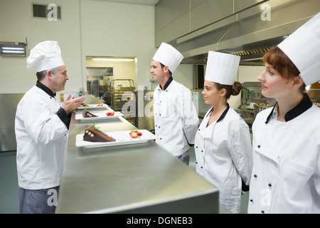 Trois chefs presenting dessert plates à leur chef Banque D'Images