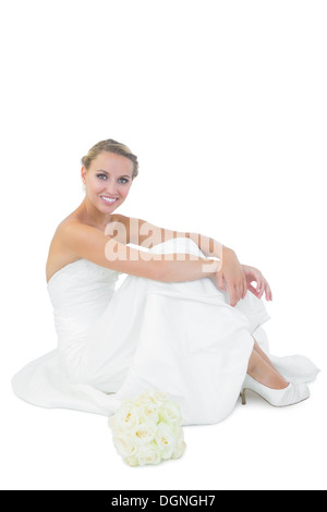 Jeune blonde bride sitting next to her bouquet Banque D'Images