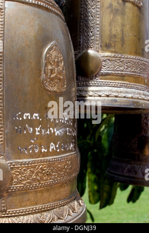 Cloches ornés avec Thai écrit sont exposées dans un temple bouddhiste à Chiang Rai, Thaïlande. Banque D'Images