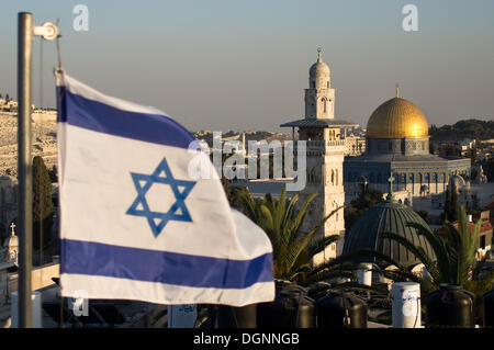 Jeruslaem, Israël. 23 Oct, 2013. Le drapeau israélien des vagues dans l'avant-plan en tant que derniers rayons de soleil sur la vieille ville de Jérusalem peindre le dôme doré de Haram al-Charif, l'un des plus importants sites religieux dans le judaïsme, le christianisme et l'Islam. Jérusalem, Israël. Credit : Alon Nir/Alamy Live News Banque D'Images