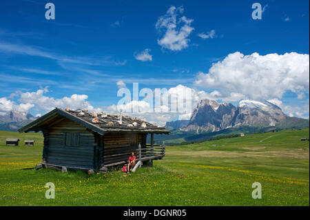 Femme assise à un chalet de montagne en face de la montagne Sasso Lungo Piatto et montagnes, Alpe di Siusi, Dolomiten Banque D'Images