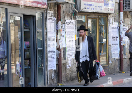 Scène de rue avec un Juif orthodoxe dans l'un me'shéarim district, avec des maisons typiques et journaux muraux, Jérusalem, Israël Banque D'Images
