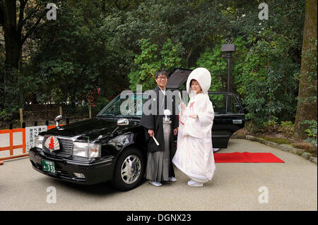 Couple japonais en kimonos, suite nuptiale avec capot et kimono avec brocade, debout devant la voiture de mariage avec un tapis rouge Banque D'Images