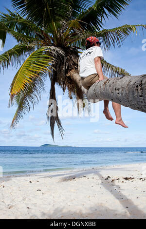 Femme assise sur un cocotier, arbre Anse Fourmis, La Digue, Mahé, Seychelles, Afrique, Océan Indien Banque D'Images