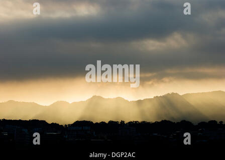 Soleil à travers les nuages gris au-dessus de montagne Banque D'Images