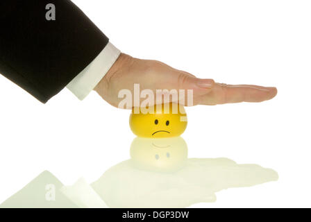 Businessman appuyant sur sa paume vers le bas sur un smiley, image symbolique pour la pression à effectuer Banque D'Images