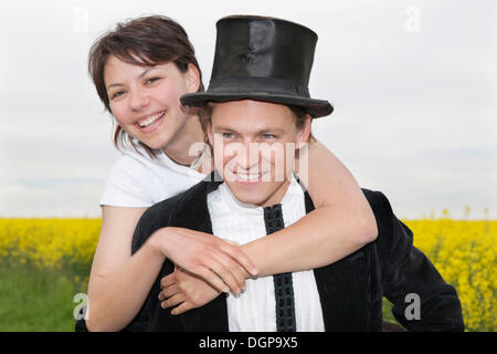 Jeune femme avec top hat embrassant son petit ami qui la transporte sur son dos Banque D'Images