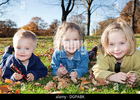 Garçon, 2, avec ses soeurs, 4 et 6, dans un parc en automne Banque D'Images