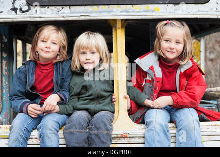 Trois enfants assis dans un bus désaffecté, Esslingen, Bade-Wurtemberg, Allemagne Banque D'Images