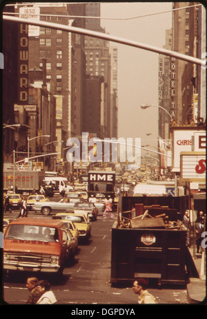 À Midtown Manhattan, un conteneur de remorque à ordures est visible au premier plan, reflétant les pratiques de gestion des déchets urbains dans une ville animée. L'image donne un aperçu de la collecte des déchets au cœur de New York. Banque D'Images