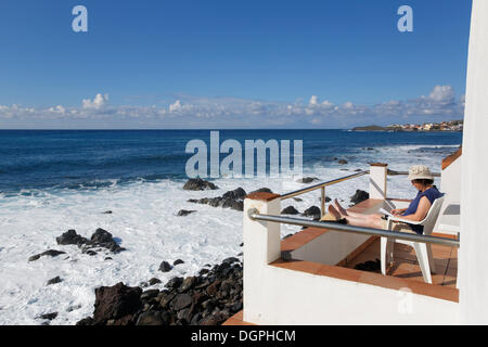 Femme assise sur un balcon par la mer, La Puntilla, Valle Gran Rey, La Gomera, Canary Islands, Spain Banque D'Images