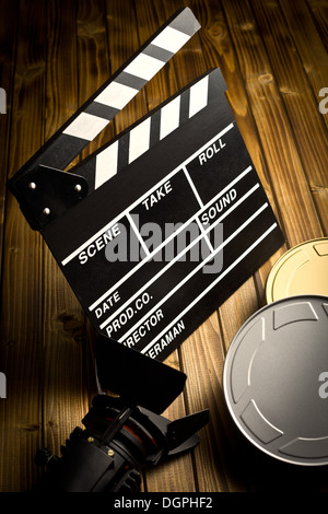 Clapper board avec film lumière et bobines de film sur table en bois Banque D'Images