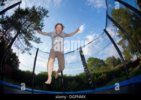 L'homme sautant sur un trampoline de jardin Banque D'Images