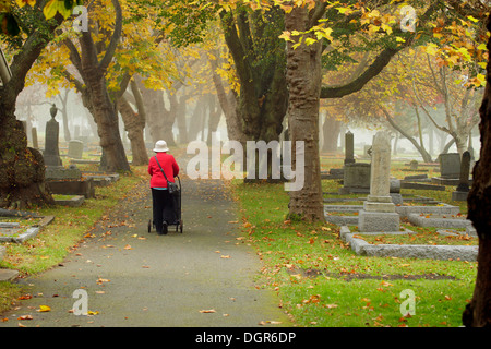 Woman panier en chemin par Ross Bay cimetière en automne -Victoria, British Columbia, Canada. Banque D'Images