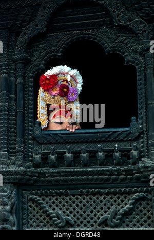 Dieu vivant de Katmandou, Bhairava, lorgnant par la fenêtre en bois joliment sculpté. Banque D'Images