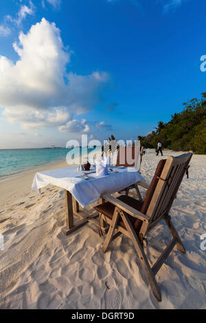 Une table dressée pour le dîner debout sur la plage, le Paradise Island à l'arrière, Lankanfinolhu, North Male Atoll Banque D'Images