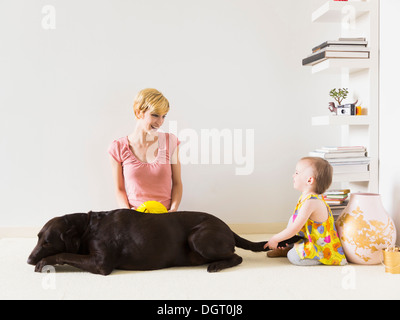 Mère avec bébé fille (4-5) Playing with dog Banque D'Images