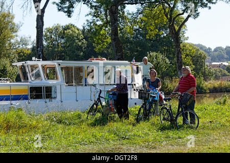 Les vacanciers en face d'une maison bateau sur le canal des Vosges, anciennement Canal de l'Est, après faire du shopping à vélo Banque D'Images
