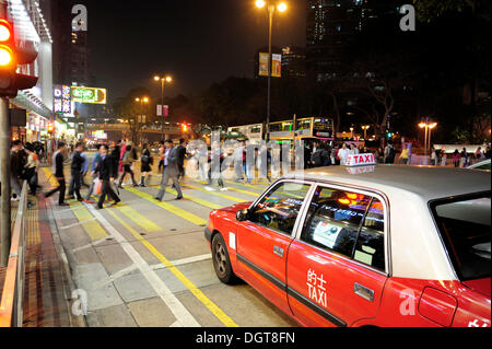 Un taxi rouge en attente à un passage clouté sur Chatham Road dans la soirée, Tsim Sha Tsui, Kowloon, Hong Kong, Chine, Asie Banque D'Images