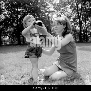 La mère et le garçon, 5 ans, boire d'une bouteille dans un pré, Leipzig, Allemagne de l'est photographie historique autour de 1976 Banque D'Images