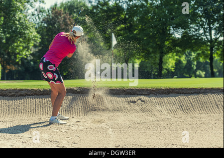 Golfeur frapper la balle du bunker Banque D'Images