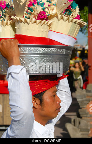 L'hindouisme balinais, pieuse jeune homme portant un bol sacrificiel d'argent avec des cadeaux sur sa tête, Pura Ulun Danu Batur temple Banque D'Images